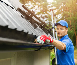 A worker cleaning a gutter